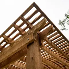 Drewniana pergola z ozdobnymi elementami. Dowiedz się, jak suszyć drewno, żeby nie pękało, by cieszyć się trwałą konstrukcją.