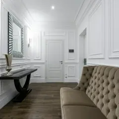 Elegancka sztukateria na ścianach inspiracje: korytarz z sofą, konsolą i lustrem.