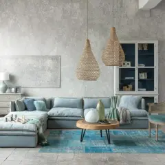 Nowoczesny styl prowansalski w salonie: błękitna sofa, plecione lampy, drewniany stolik i kamienna podłoga tworzą przytulną atmosferę.