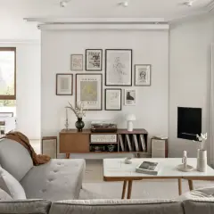 Salon w stylu retro inspiracje: szara kanapa, drewniana komoda z gramofonem i płytami, galeria ścienna z grafikami, stolik kawowy.