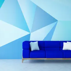 Niebieska sofa i geometryczne malowanie ścian – świetne malowanie ścian inspiracje. Roślina w donicy i lampa dopełniają nowoczesny wystrój.