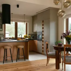 Nowoczesna kuchnia w stylu modern farmhouse z drewnianą wyspą, szarymi frontami i dużym oknem z widokiem na las.