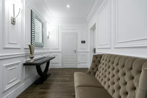 Elegancka sztukateria na ścianach inspiracje: korytarz z sofą, konsolą i lustrem.