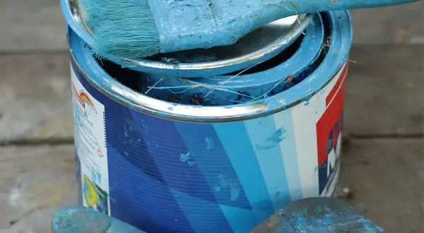 Puszka z niebieską farbą lateksową i pędzel. Zastanawiasz się, czym zmyć farbę lateksową? Woda z mydłem często wystarcza.