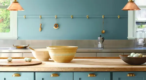 Niebieskie szafki kuchenne, drewniany blat, misy i jajka. Ściana pomalowana farbą ceramiczną w odcieniu błękitu.