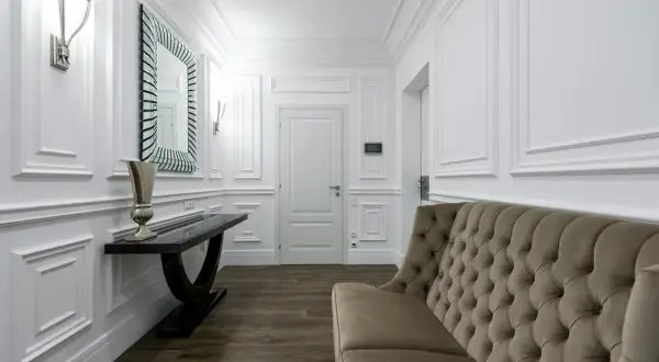 Elegancka sztukateria na ścianach inspiracje: korytarz z sofą, konsolą i lustrem.