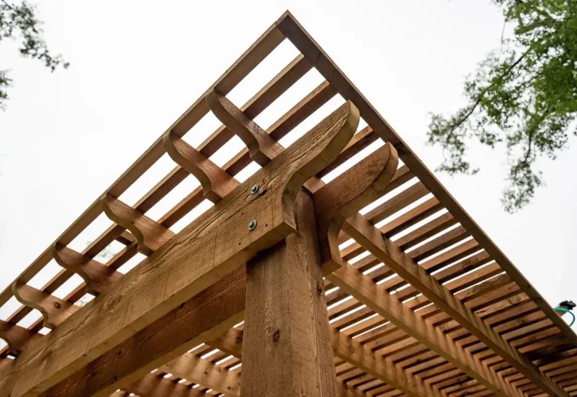 Drewniana pergola z ozdobnymi elementami. Dowiedz się, jak suszyć drewno, żeby nie pękało, by cieszyć się trwałą konstrukcją.