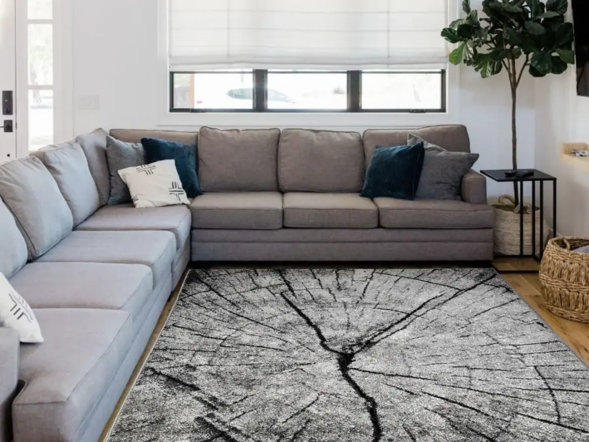 Nowoczesny dywan w salonie zasady, imitujący przekrój drzewa, idealnie komponuje się z szarą sofą i minimalistycznym wystrojem.