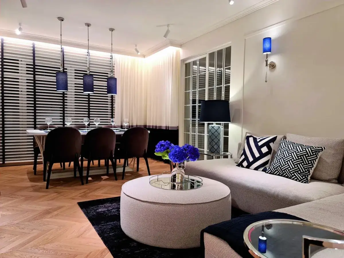 Eleganckie wnętrze z jadalnią i salonem. Trzy wiszące lampy nad stołem, wygodna kanapa z geometrycznymi poduszkami. Inspirujące miruć projekty.