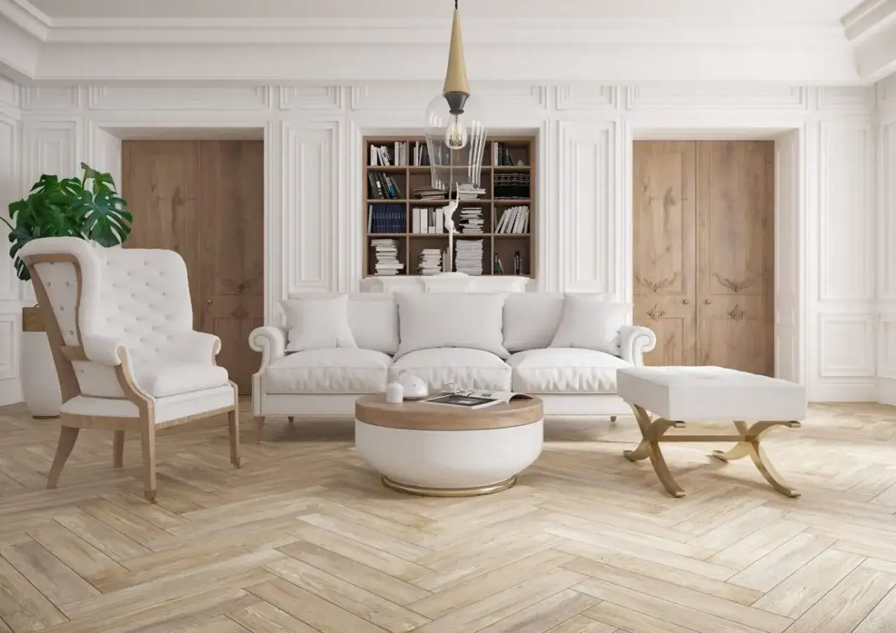 Eleganckie wnętrze z białymi meblami i sztukaterią na ścianach. Inspiracje do salonu z książkami i drewnianymi drzwiami.