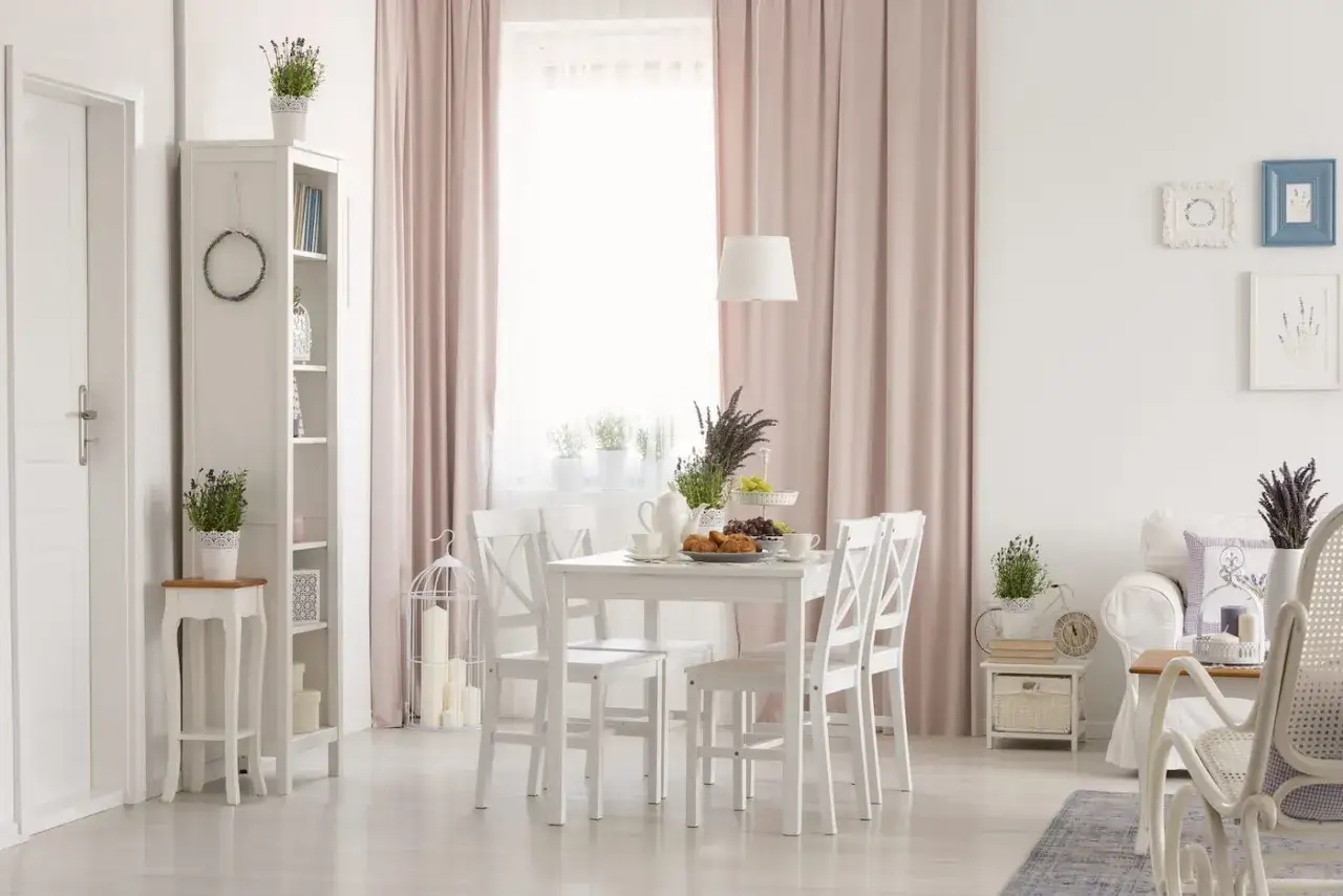 Jasny, przytulny salon w stylu prowansalskim. Białe meble, pastelowe zasłony i lawenda tworzą sielską atmosferę.