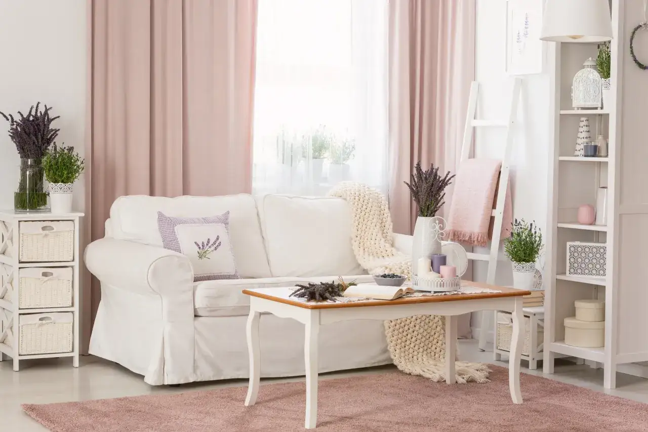 Przytulny salon w stylu prowansalskim z białą kanapą, stolikiem kawowym i bukietami lawendy.
